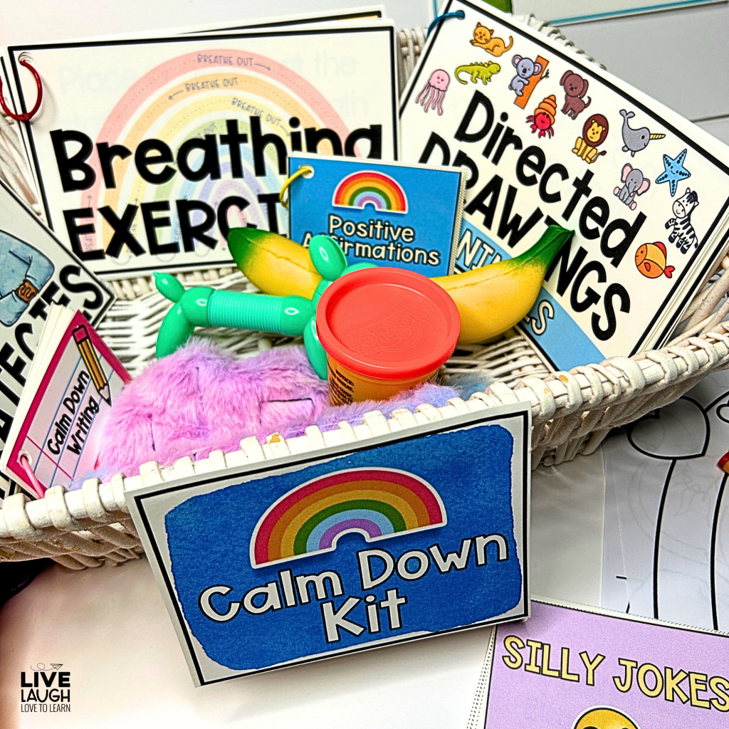 A close-up of a Calm Down Kit in a white wicker basket, filled with various emotional regulation tools and activities. The kit includes laminated breathing exercises, directed drawing prompts, a positive affirmations flipbook, and a calm down writing activity. Sensory items such as a plush purple fidget, a small container of Play-Doh, and a green-and-yellow banana-shaped stress toy are also included. A blue sign with a rainbow illustration and 'Calm Down Kit' label is attached to the basket, creating an inviting space for students to self-regulate.