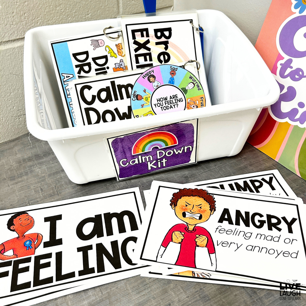 A Calm Down Kit in a white plastic bin, filled with emotional regulation tools such as breathing exercises, directed drawings, and an emotions wheel for self-check-ins. Several emotion cards are spread out in front of the bin, including one labeled 'ANGRY' with an illustration of a frustrated child. The bin is labeled with a colorful 'Calm Down Kit' sign featuring a rainbow. A bright, motivational sign in the background reads 'It's Cool to be Kind,' reinforcing a positive classroom environment.