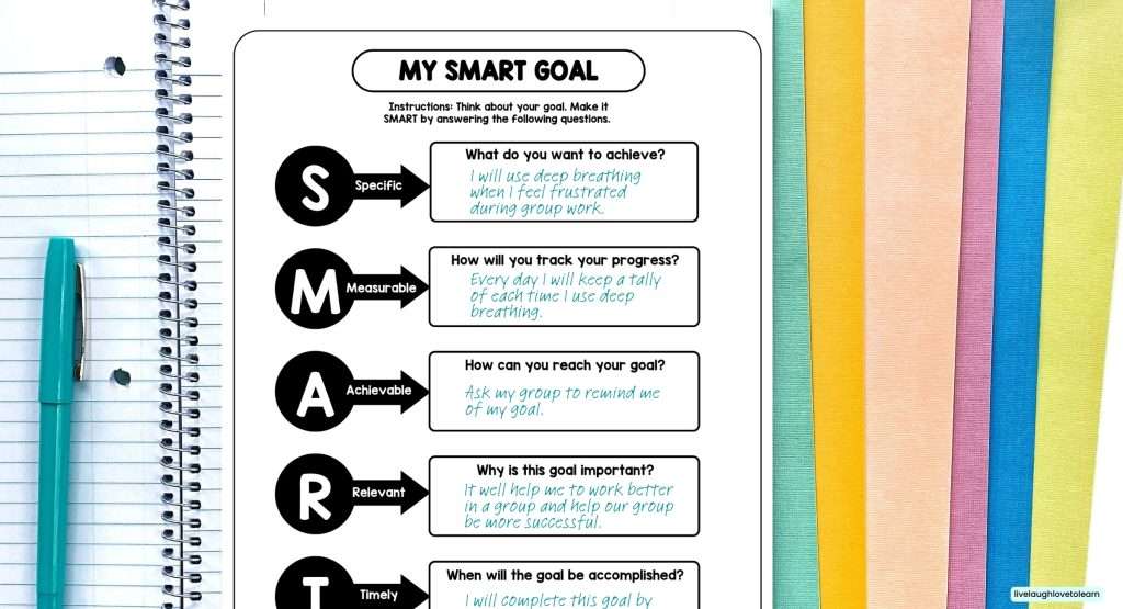 Open student notebook displaying a “My SMART Goal” worksheet with sections for Specific, Measurable, Achievable, Relevant, and Timely goals. The first box example reads, “I will use deep breathing when I feel frustrated during group work.” The notebook is surrounded by colorful pastel paper, a teal pen,creating a bright and cheerful workspace.
