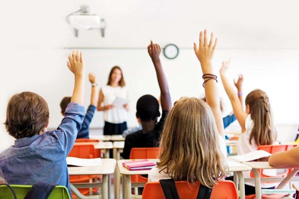 Students raising their hands during a classroom discussion, practicing listening and using their voices during a lesson on student voice.