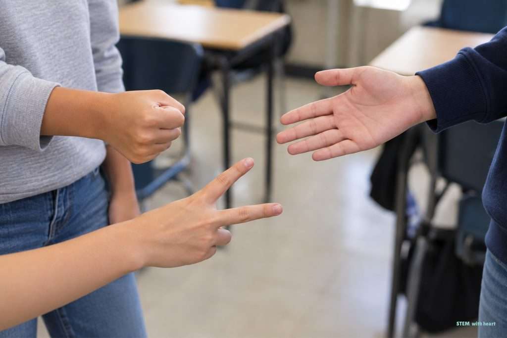 Students playing Rock, Paper, Scissors as a quick decision-making strategy during a STEM group activity.